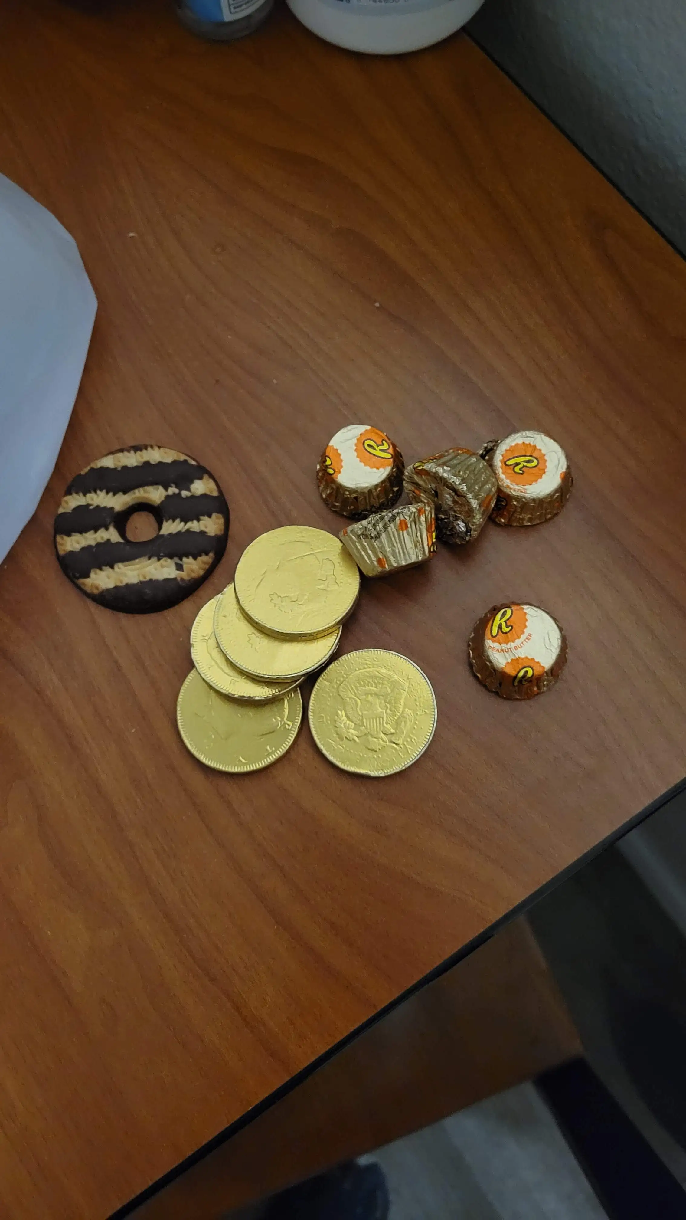 a wooden table topped with various wrapped chocolates and a chocolate stripped cookie